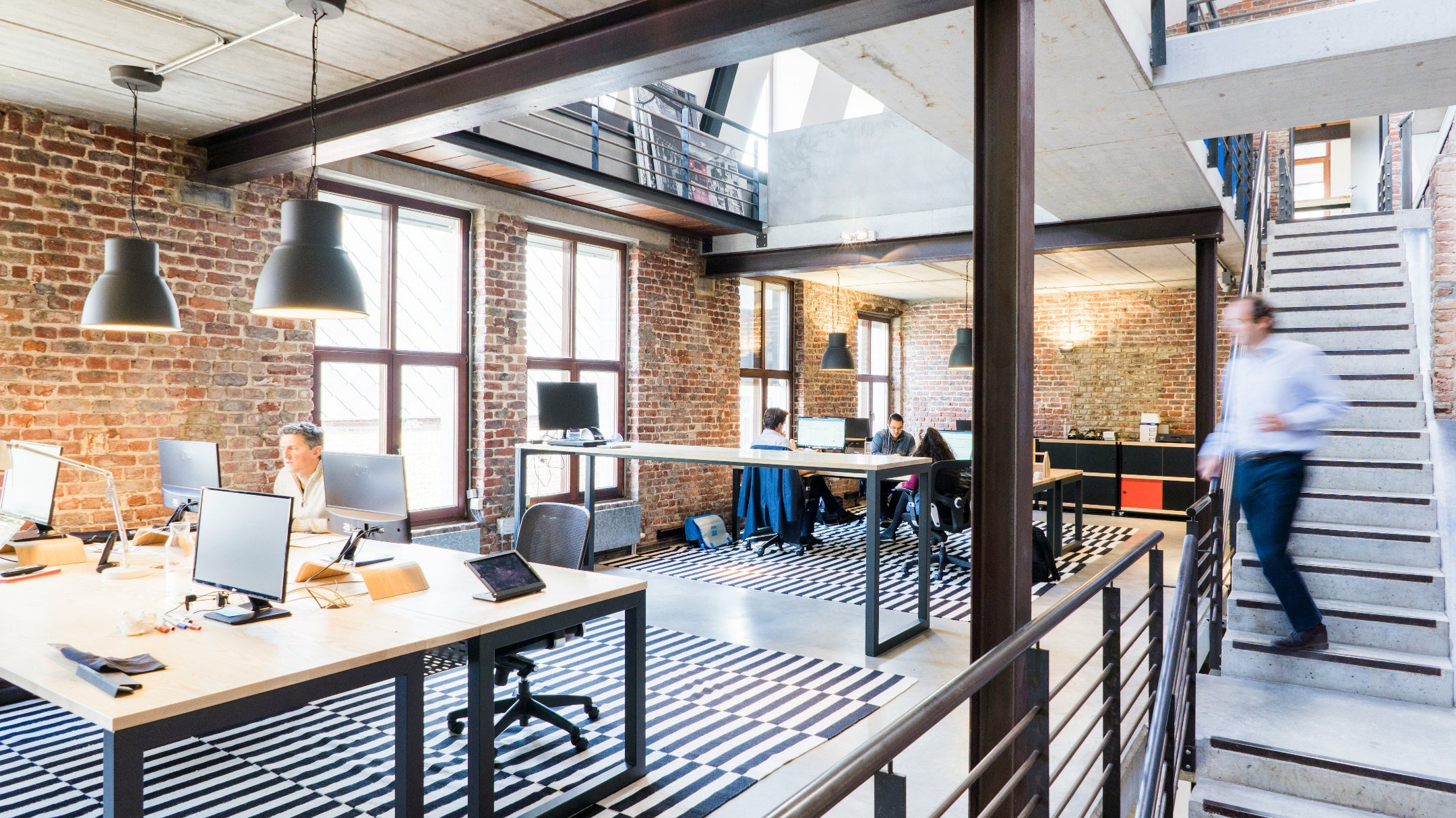 Modern office space with brick walls, glass windows, and a staircase.