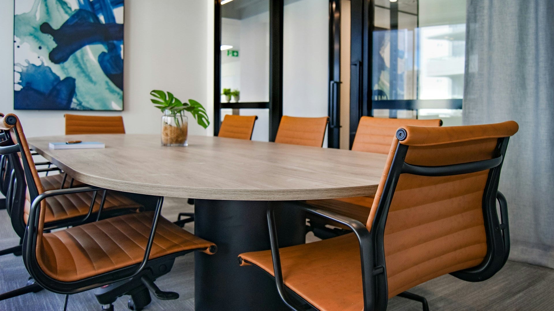 Modern conference room with a round wooden table and orange chairs.